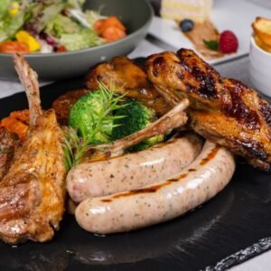 Delicious gourmet meat platter with sausages, lamb chops, and vegetables, perfect for a hearty meal.